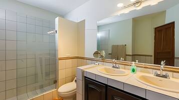 A modern bathroom with a glass shower enclosure, a toilet, a sink with a mirror, and a vanity.