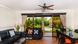 A living room with a black sofa, a glass coffee table, and a dining area with a table and chairs. - Coco Sunset Hills 52 (Coco)