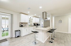 Enjoy cooking in this well-equipped kitchen with a large island, stainless steel range hood, and ample counter space.