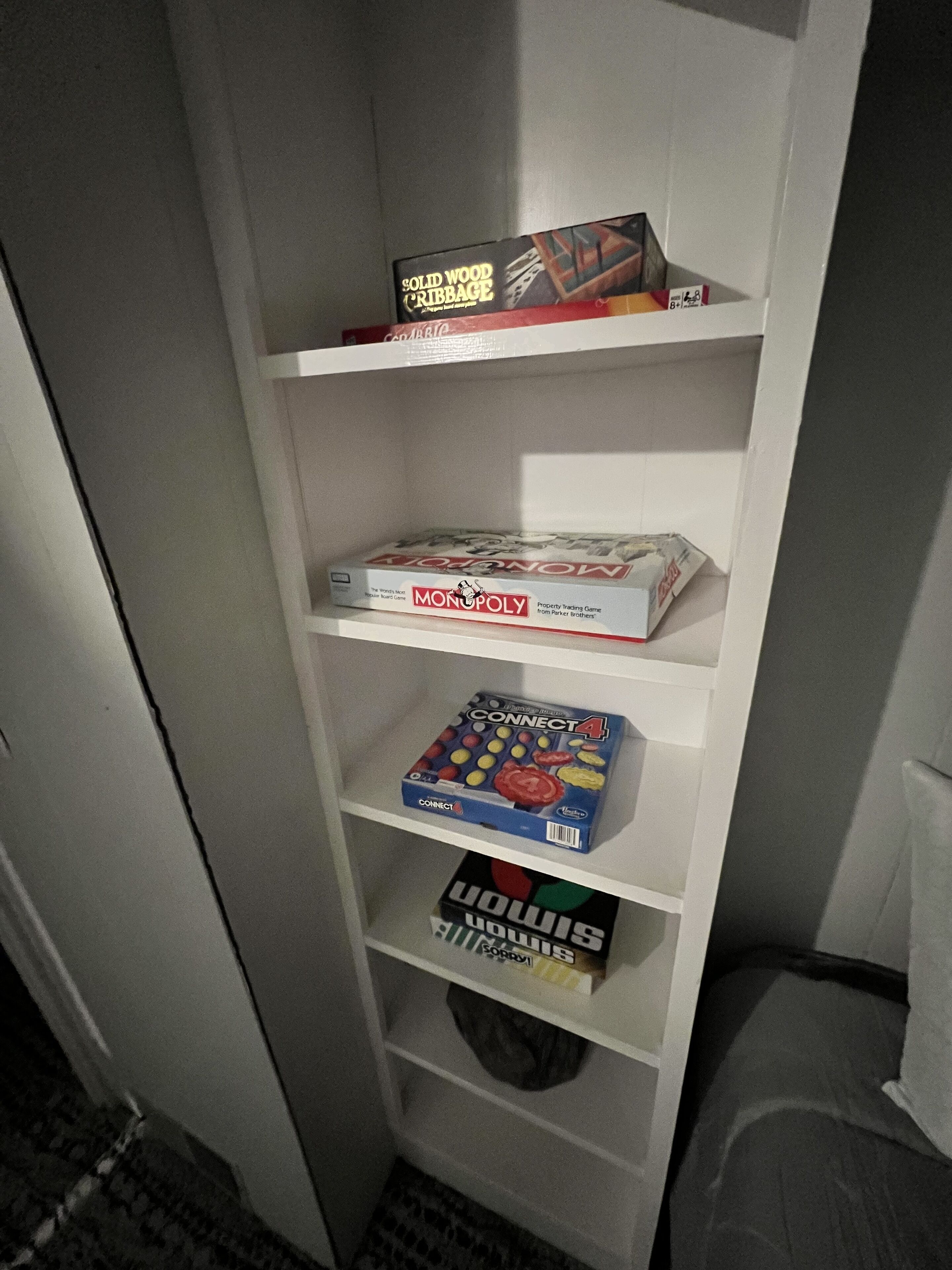 Una estantería con juegos de mesa, incluyendo Monopoly, Connect 4 y otros.