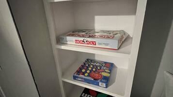 Una estantería con juegos de mesa, incluyendo Monopoly, Connect 4 y otros.