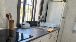 Une cuisine moderne dotée d’un plan de travail noir, de meubles blancs, d’un four à micro-ondes encastré et d’un réfrigérateur.