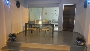 Un intérieur moderne comprenant un coin repas, un escalier menant à une porte et des plantes en pot.