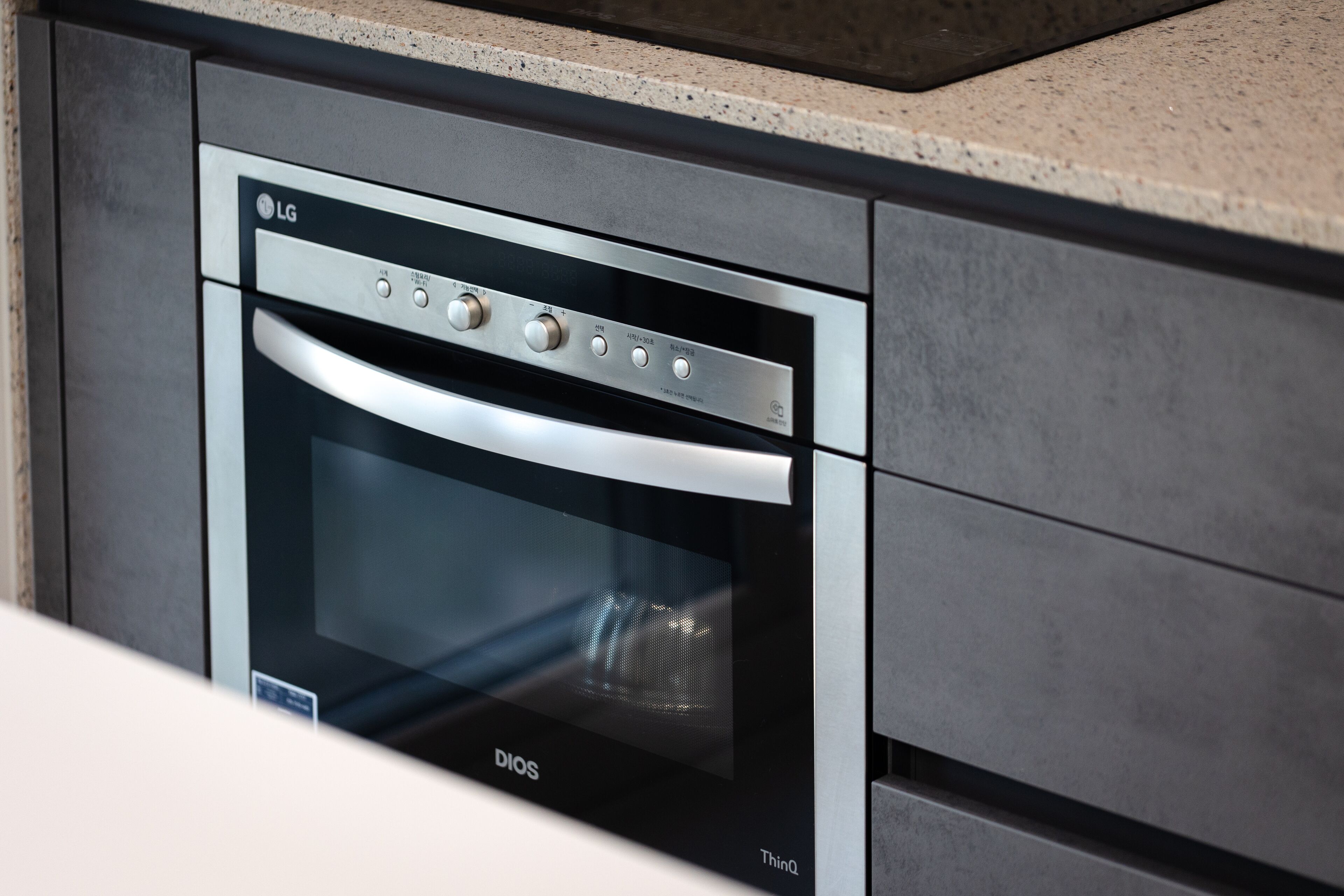 A modern kitchen with an integrated oven and microwave, featuring a sleek design and a granite countertop.