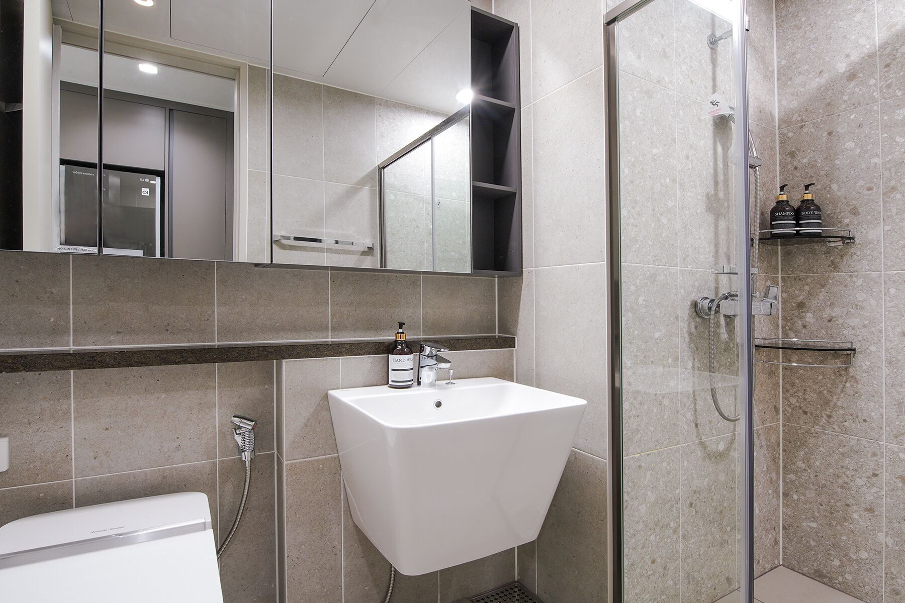 A modern bathroom with a white sink, a glass shower enclosure, and a large mirror above the sink.