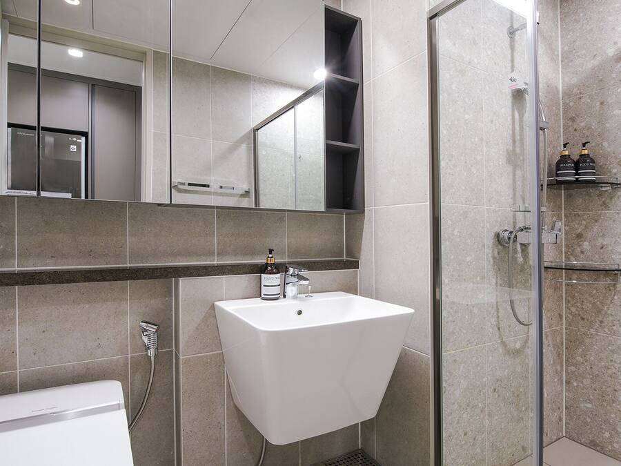 A modern bathroom with a white sink, a glass shower enclosure, and a large mirror above the sink.