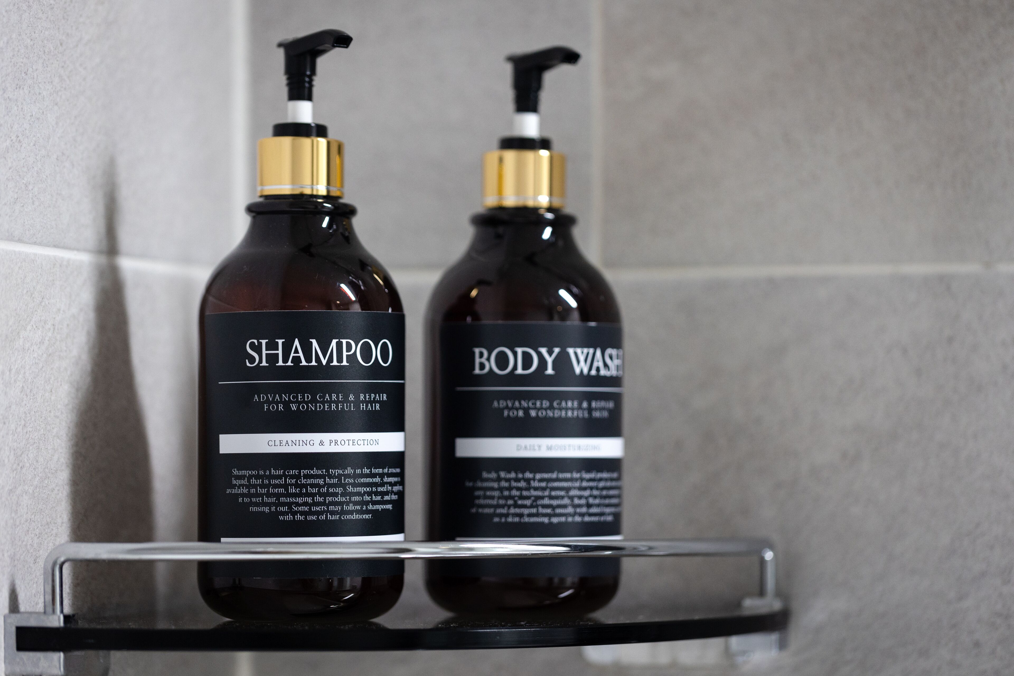 Two bottles of shampoo and body wash on a bathroom shelf.