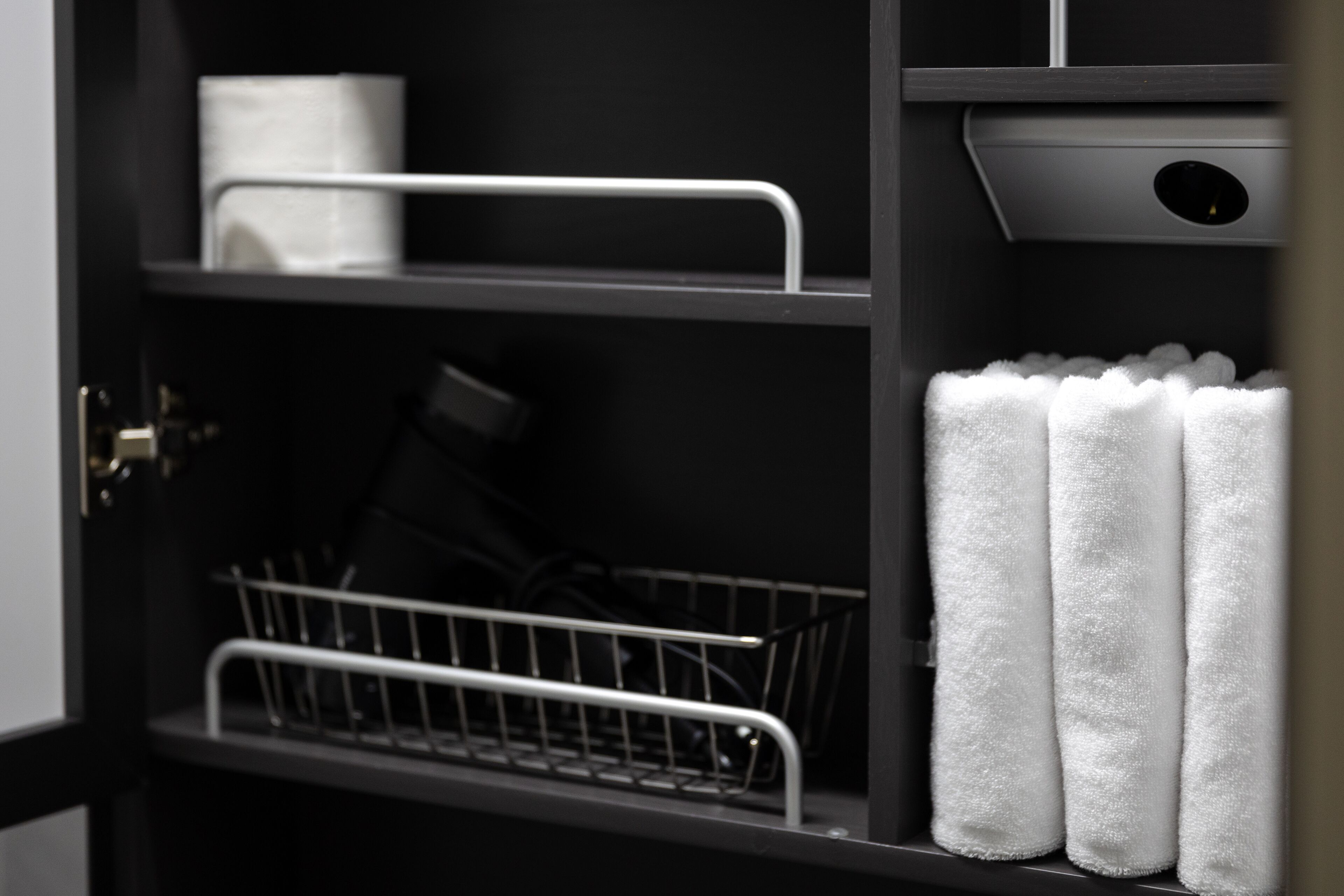 A black metal shelf with white towels and a basket.