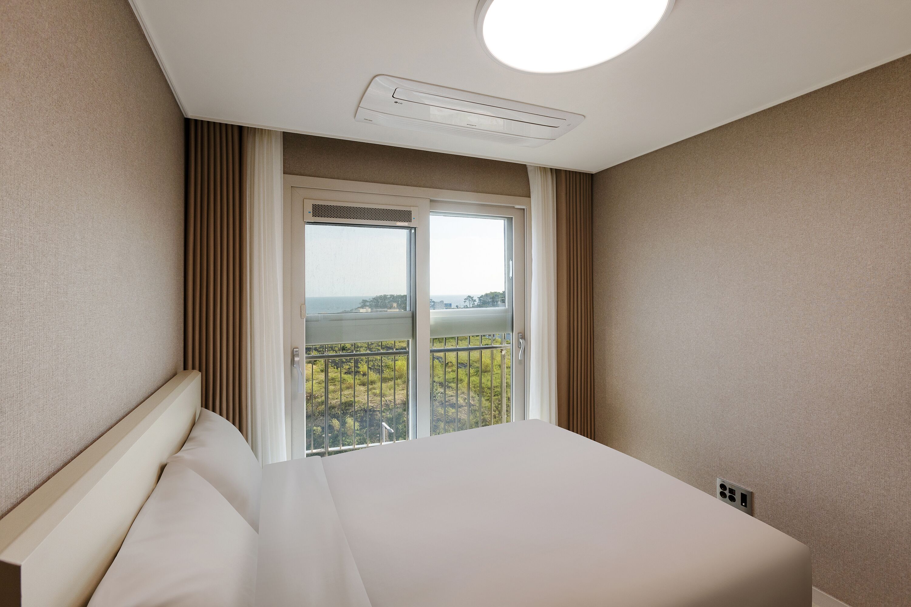 Una habitación de hotel con una cama grande, una ventana con vistas al exterior y una lámpara en el techo.