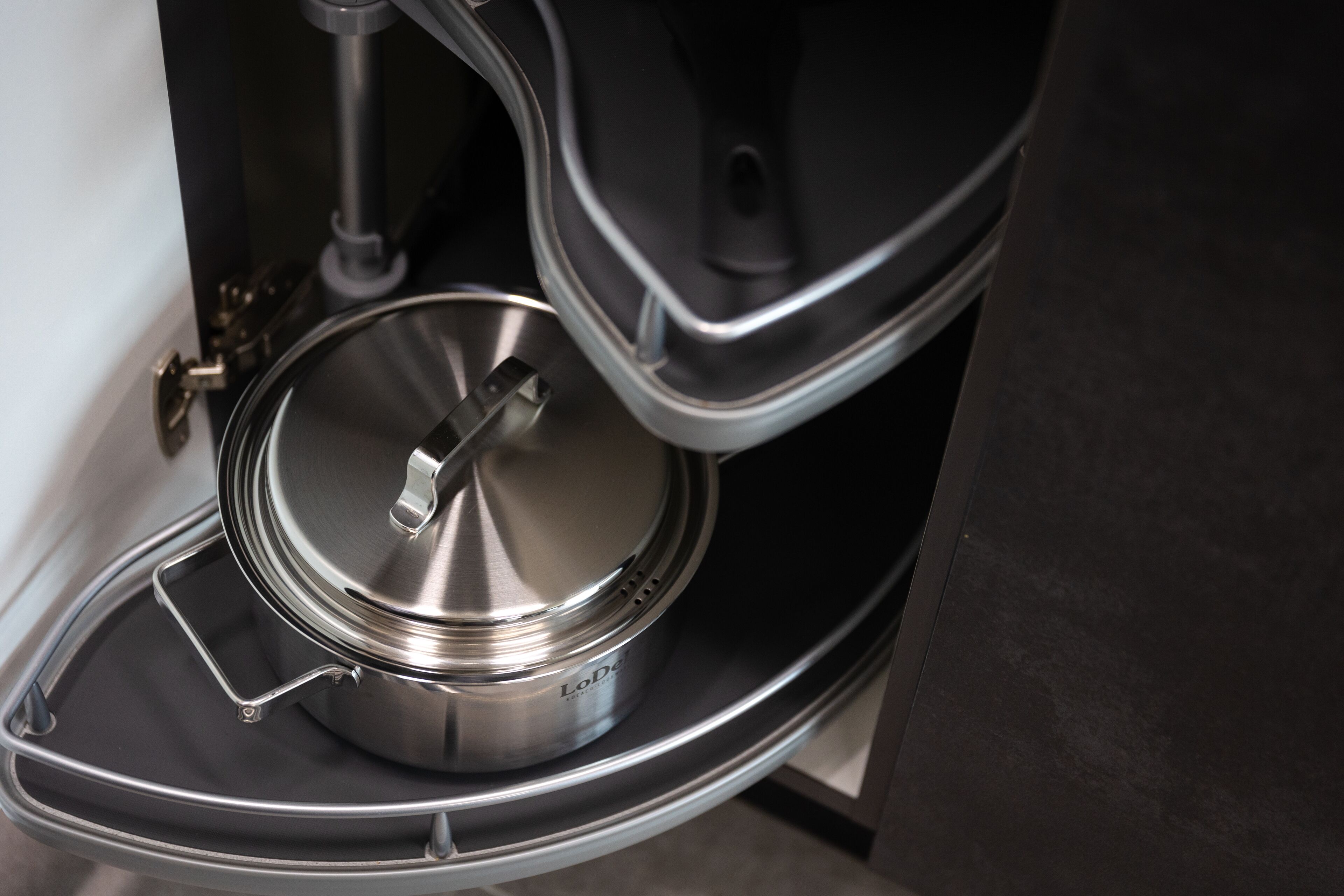 Una olla de acero inoxidable sobre una bandeja negra dentro de un electrodoméstico de cocina.