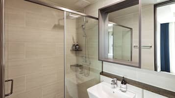Un baño moderno con cabina de ducha de vidrio, un espejo grande y un lavabo blanco.
