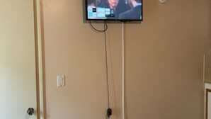Television on asennettu seinälle, ja sen alla näkyy johto sekä pistorasia.