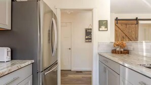 A kitchen with a stainless steel refrigerator, a toaster, and a wooden door. - Quiet 2BR cottage, King Bed, Fire, <1 mi to Sugar (Avery County)