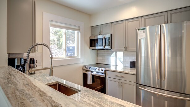 A modern kitchen with stainless steel appliances, a marble countertop, and a window providing natural light. - Quiet 2BR cottage, King Bed, Fire, <1 mi to Sugar (Avery County)