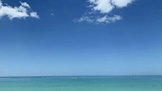 Cel blau clar sobre un mar tranquil amb un vaixell al cap i una bóia.