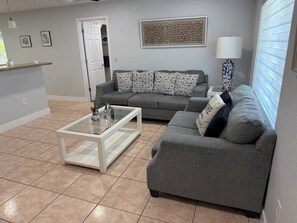 A living room with a grey sofa, a glass coffee table, and a white door.