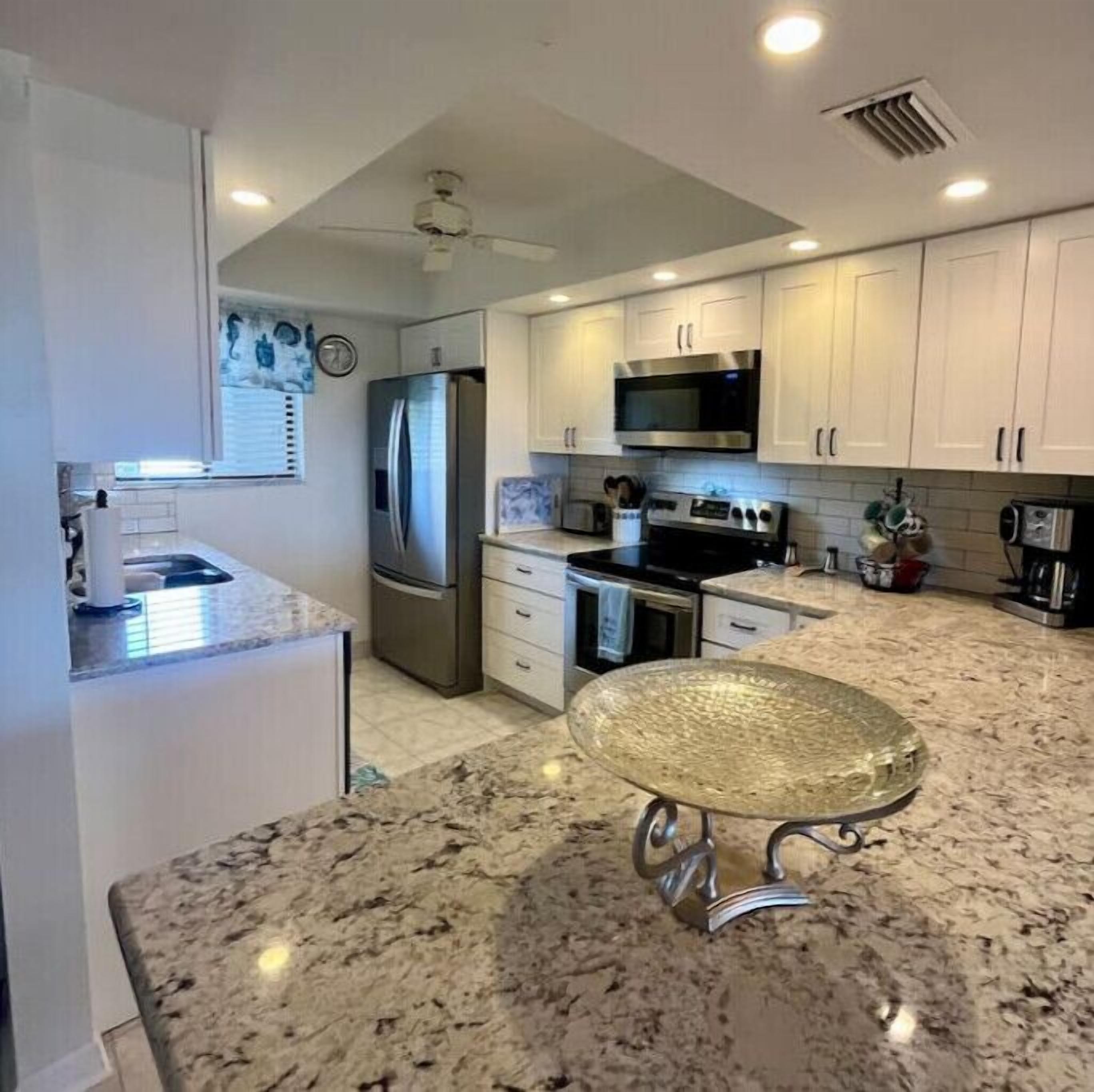 A modern kitchen with white cabinets, stainless steel appliances, and a granite countertop.