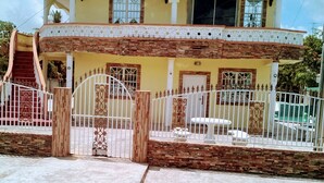 A two-story house with a balcony, a gated entrance, and a staircase leading to the upper floor. - 1st Floor 1-Bedroom ,Comfortably Sleeps 4 (Georgetown)