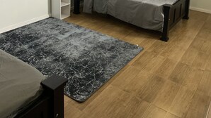 A bedroom with a bed, a nightstand, a small table with a vase, a ceiling fan, and a wall-mounted air conditioner. - 1st Floor 1-Bedroom ,Comfortably Sleeps 4 (Georgetown)