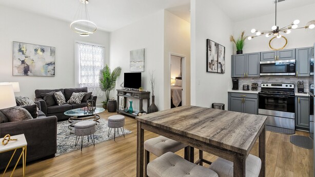 A modern living room with a dark sofa, round coffee table, and a wooden dining table with benches.