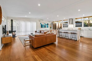 Relax in a spacious living area with a large sofa and coffee table, and cook in a well-equipped kitchen with an island and bar stools.