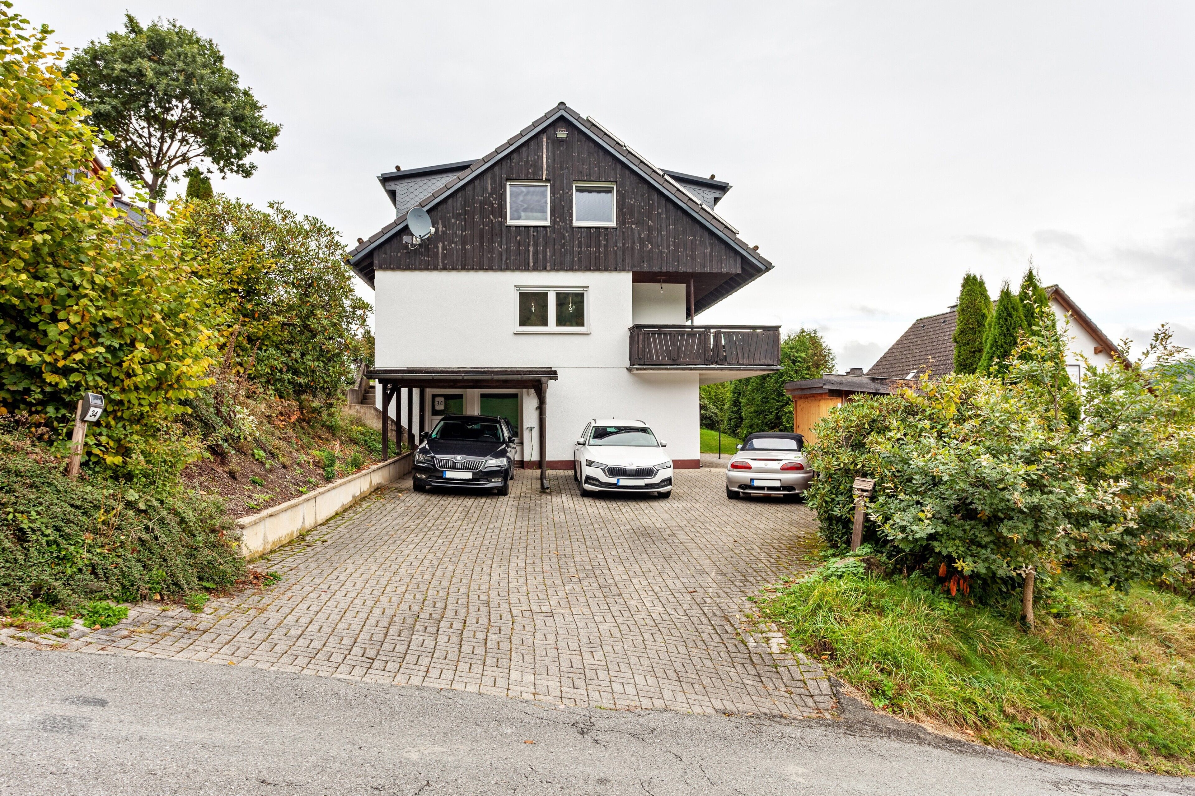 Ein zweistöckiges Haus mit Garage, Auffahrt und Garten.