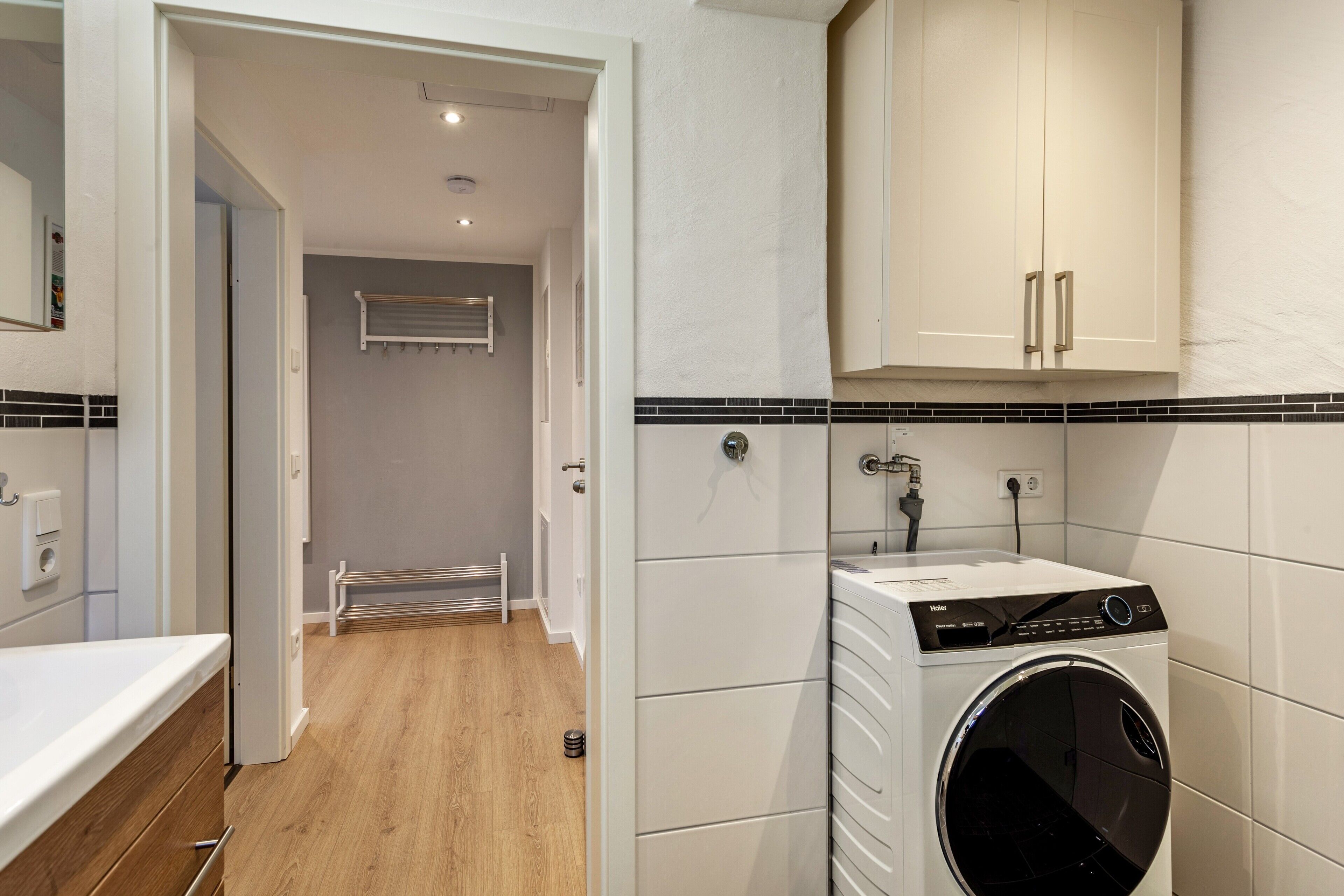 A laundry room with a front-loading washer and dryer, a towel rack, and a tiled backsplash.
