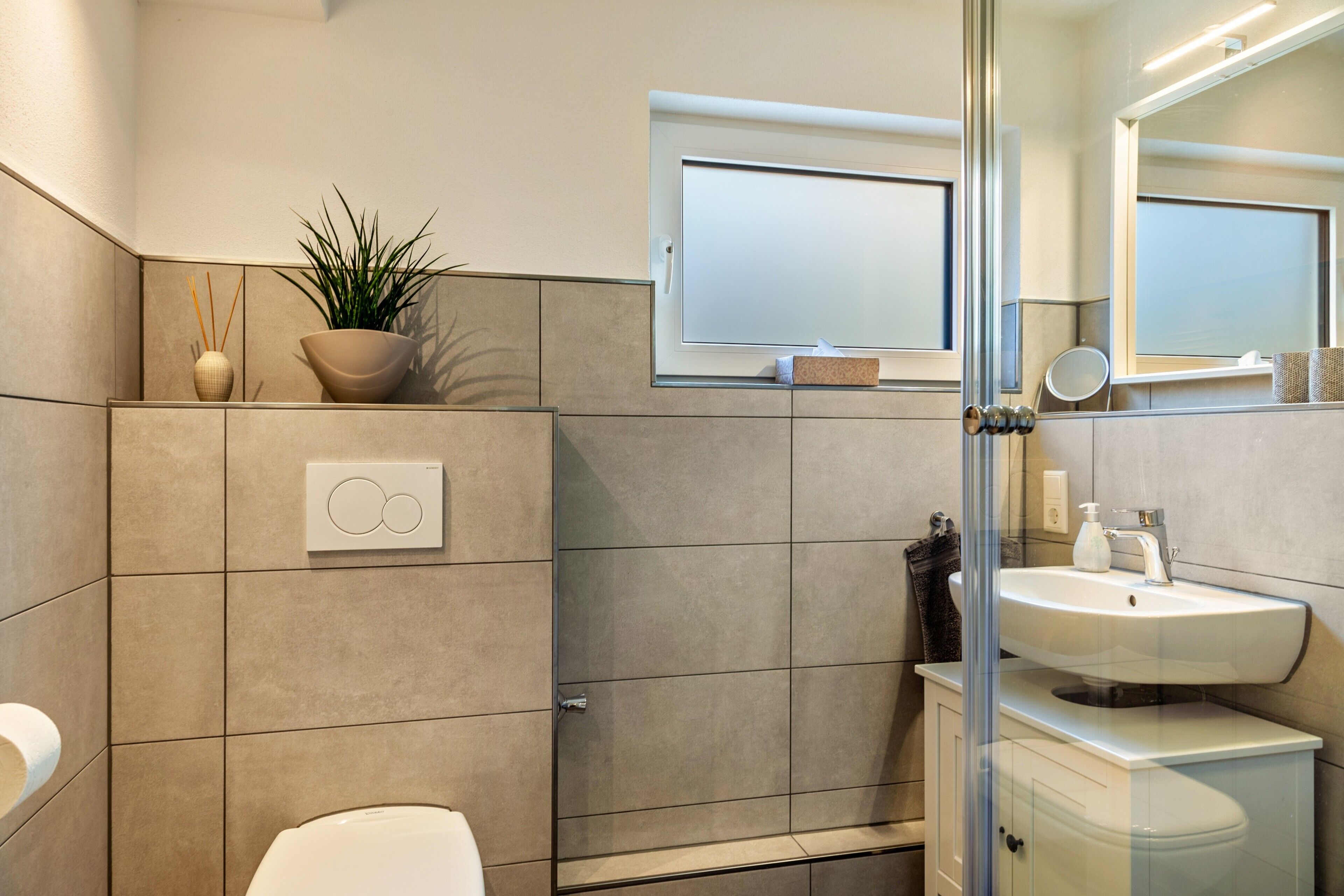 Un bany modern amb vàter, rentapel i una cabina de dutxa de vidre.