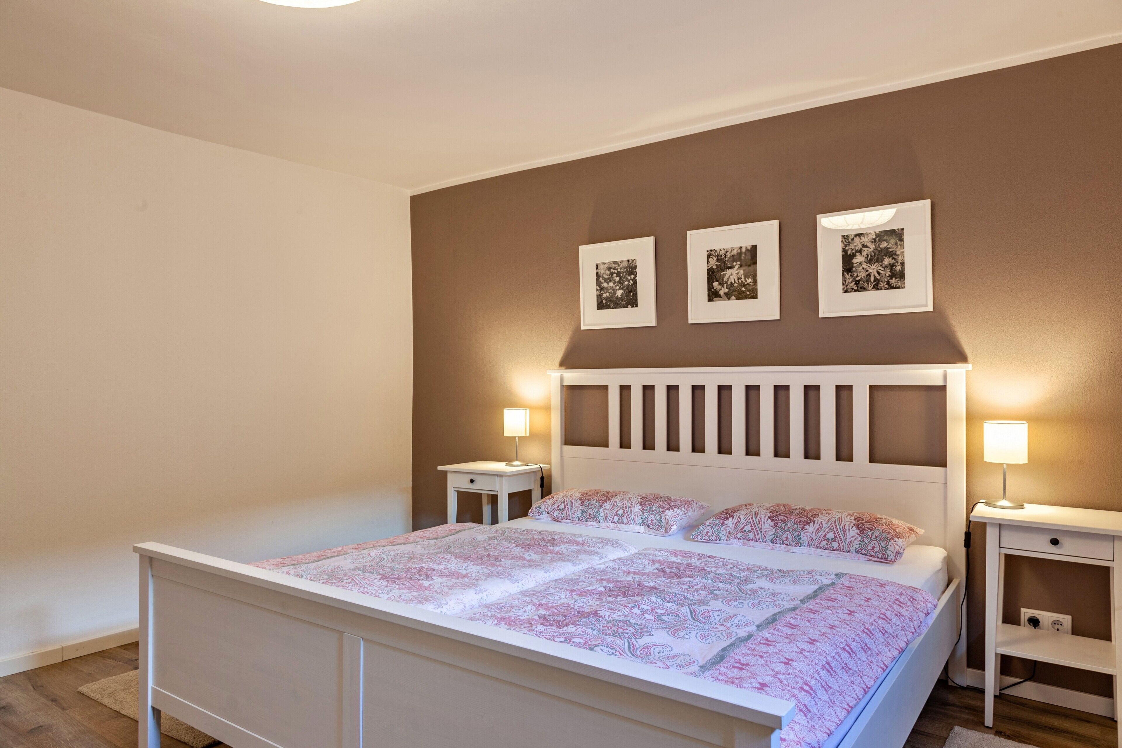 Camera da letto con un letto, comodini e quadri appesi al muro.