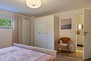 Um quarto com uma cama, um guarda-roupa, uma cadeira e um quadro.