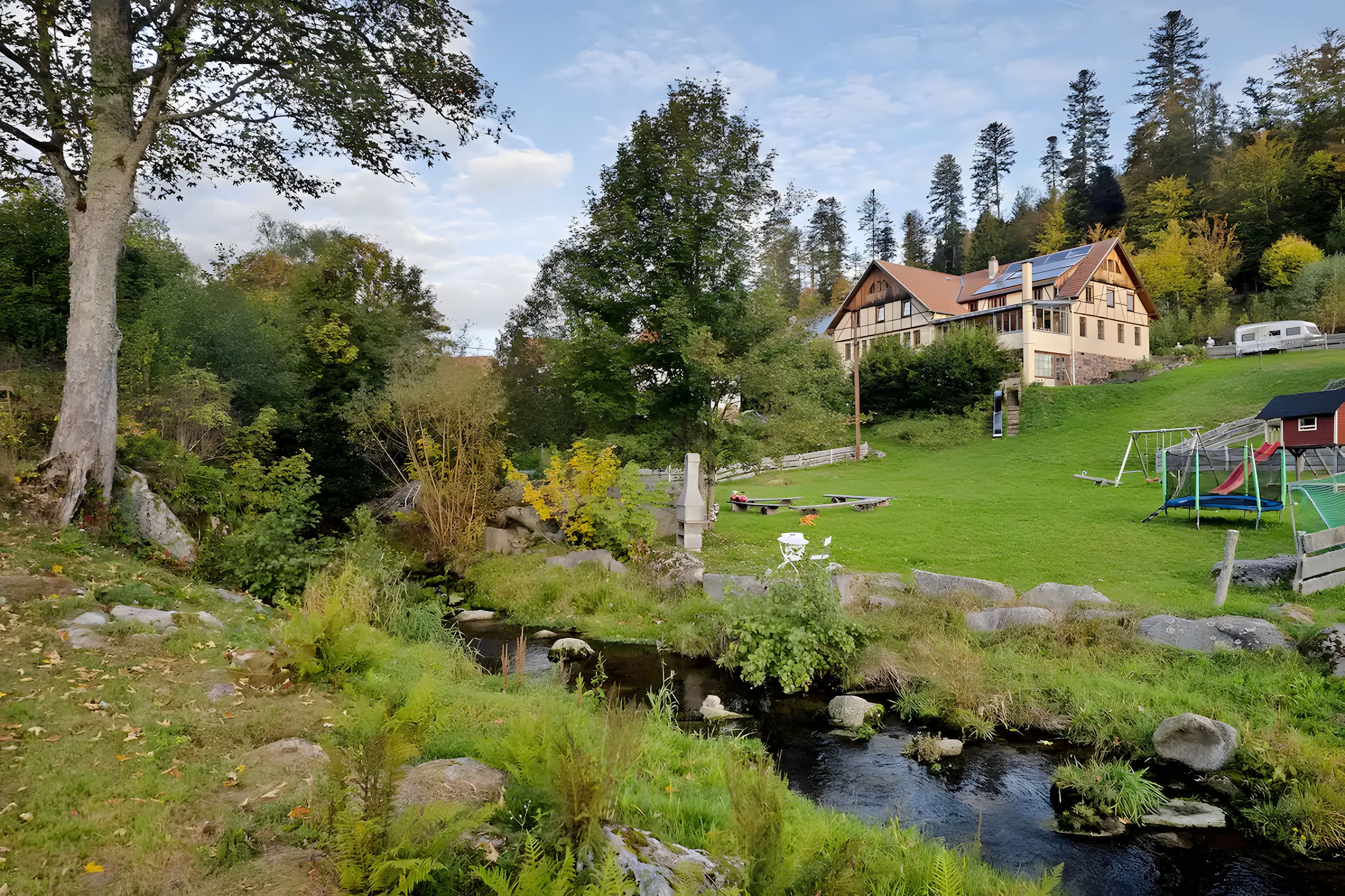 A house with a garden, a small stream, and a playground.