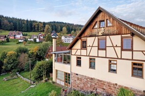 A traditional half-timbered building with a balcony, surrounded by a lush green landscape and a forested hill in the background. - Apartment 'Familienwohnung Nala' with Mountain View, Shared Garden and Wi-Fi (Forbach)