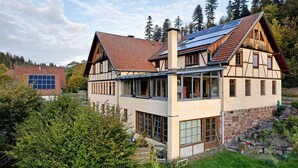 Een klassiek chalet met een schuin dak, grote ramen en een stenen fundering.