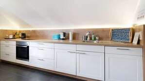Une cuisine moderne avec des armoires blanches, un four encastré, une machine à café et un évier.