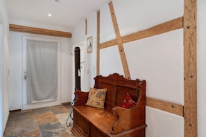 Eine Holzbank mit Kissen, eine Tür mit Vorhang und eine Wand mit freiliegenden Holzbalken.