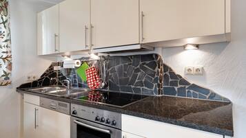 A kitchen with white cabinets, a granite countertop, a built-in oven, and a stone backsplash.