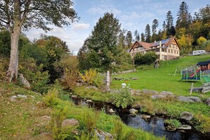 A house with a garden, a small stream, and a playground.
