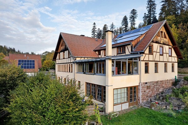 A traditional chalet with a sloped roof, large windows, and a stone foundation.