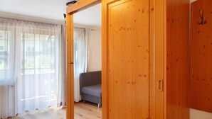 Une pièce avec un plancher en bois, un canapé gris et une armoire en bois.