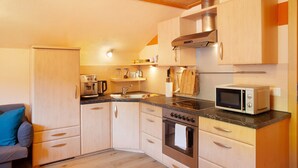 Une cuisine compacte avec des meubles en bois, un four à micro-ondes encastré, une cuisinière et un évier.