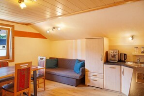 Eine kompakte Küche mit Sofa, Esstisch und Kaffeemaschine.