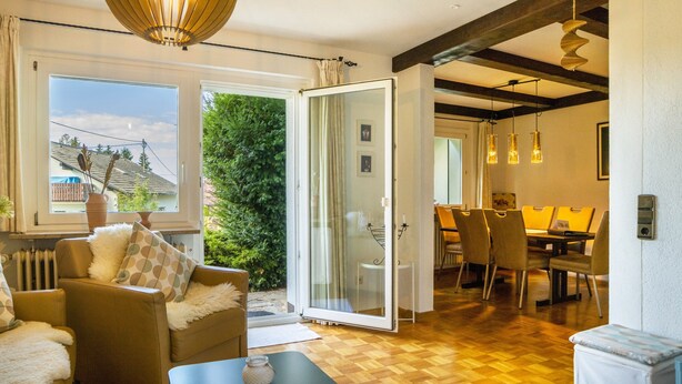 A spacious living area with a sofa, a coffee table, and a dining area with chairs and a table.