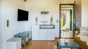 A compact living space with a flat-screen TV, a small kitchenette, a sofa, and a coffee table.