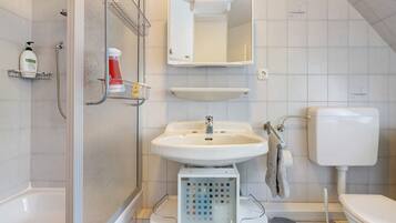 A bathroom with a shower, sink, toilet, and a mirror above the sink.
