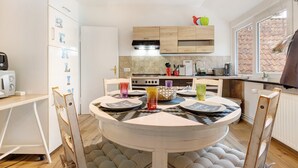 A modern kitchen with a round dining table, wooden cabinets, and a window with a view.