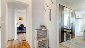 A room with a wooden floor, a desk, a chair, a mirror, and a wardrobe.