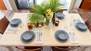 A dining table set with blue plates, silverware, and a centerpiece of flowers and greenery. - The Beach Bach – Peaceful and relaxing villa (Vincentia)