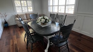 A dining room with a dark wooden table, white flowers, and six chairs. - Split Mountain View Paradise! Life on the farm! (Vernal)