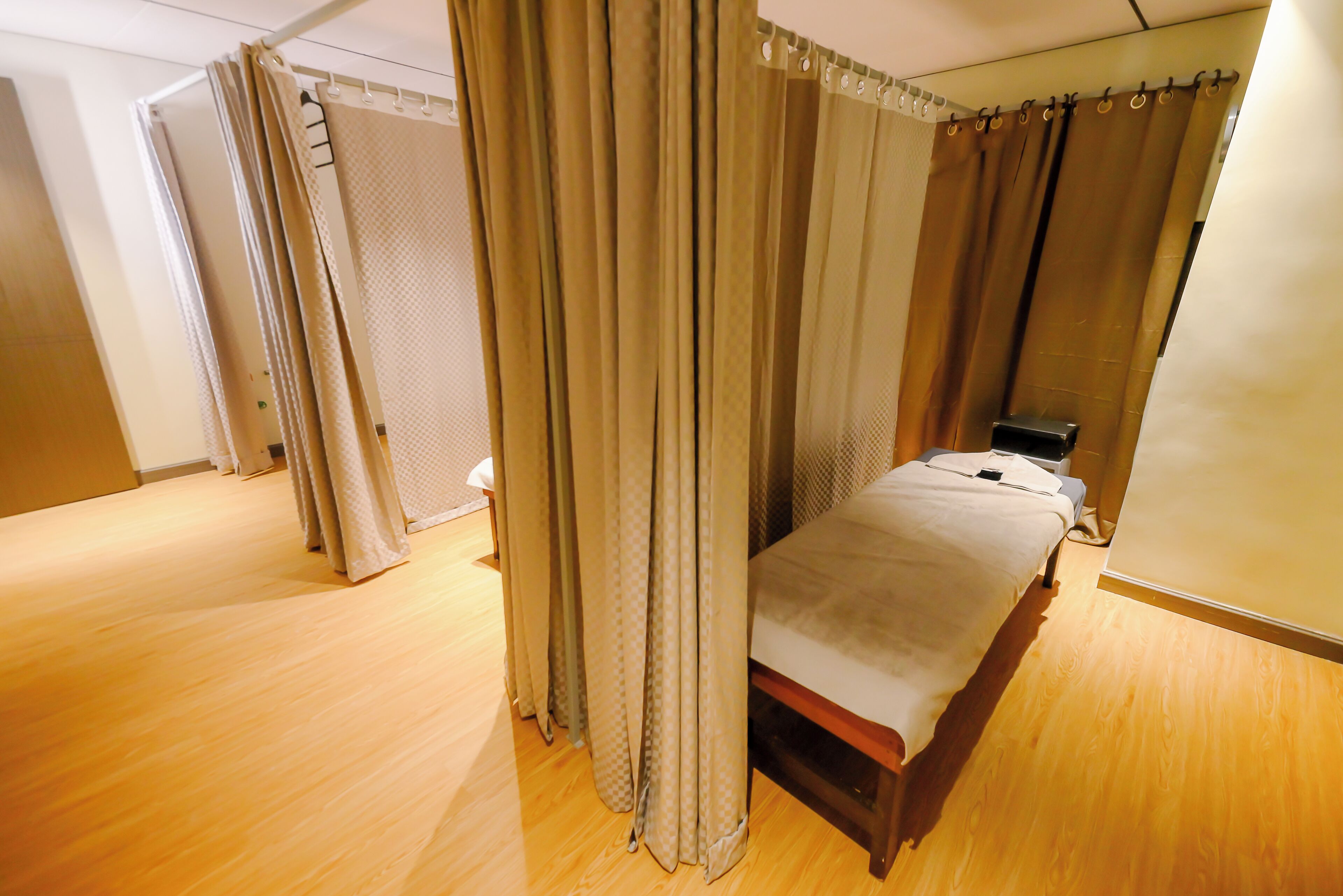 A bedroom with a bed, curtains, and a wooden floor.