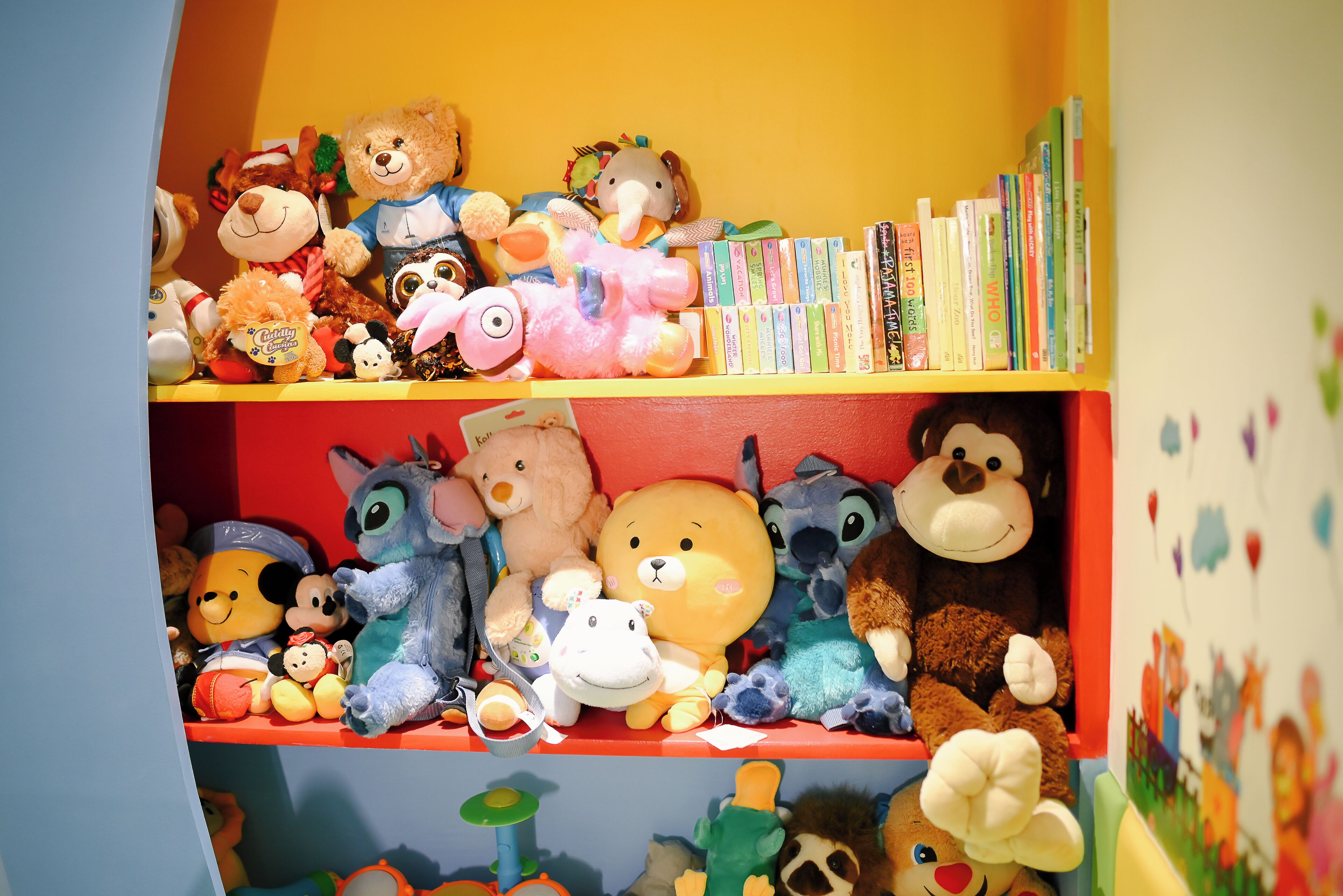 A shelf with various stuffed animals and books.